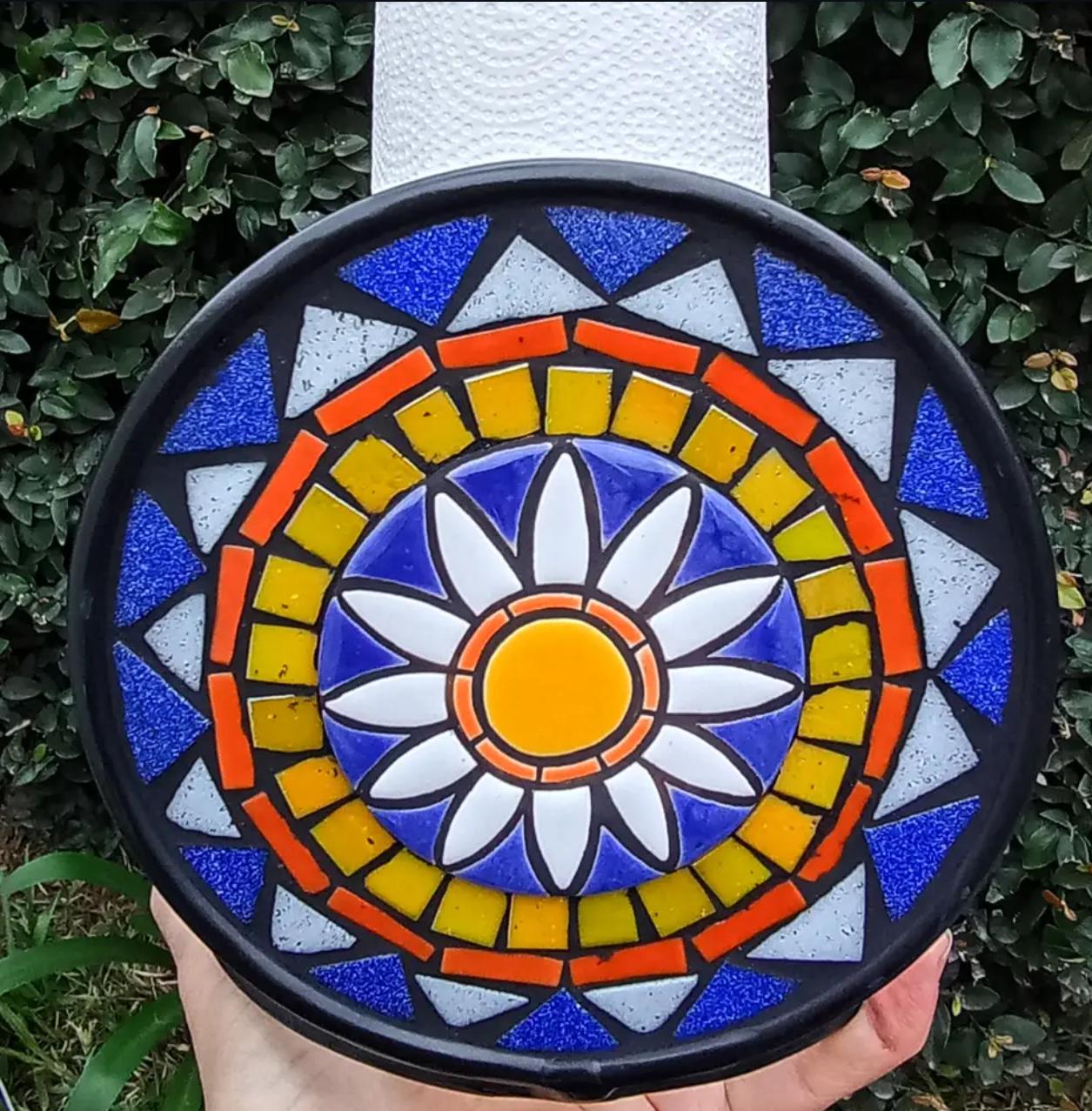 Pieza circular de mosaico geométrico en azul, amarillo y naranja